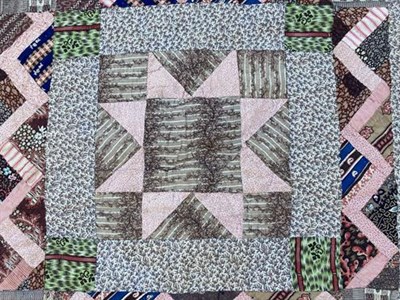 Lot 2002 - An Early 19th Century Patchwork Quilt, with a pink patchwork star to the brown floral sprigged...