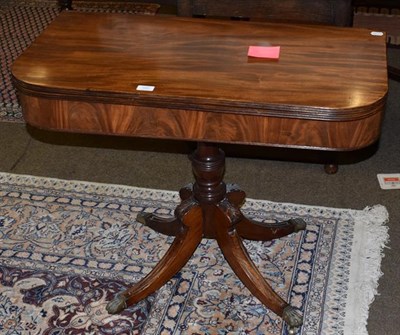 Lot 1281 - A George III mahogany fold over tea table, turned column, four out-swept leg to castors, 90cm wide