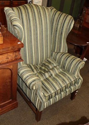 Lot 1323 - A Georgian style wing backed armchair with striped upholstery