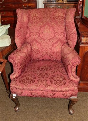 Lot 1325 - A Georgian style wingback armchair, red foliate upholstery