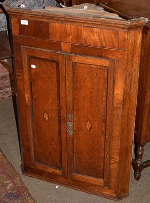 Lot 1339 - A George III oak wall hanging corner cupboard, twin crossbanded doors with inlaid shell detail,...