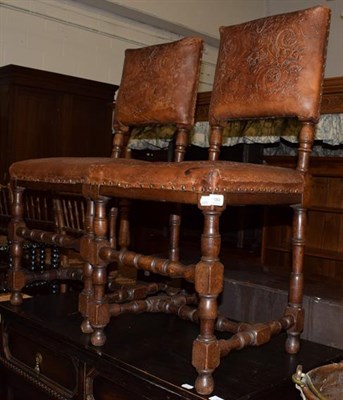 Lot 1352 - A pair of oak chairs with studded and embossed leather work decorated with leaves and scrolls