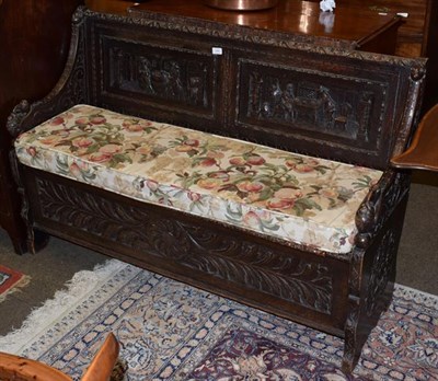 Lot 1365 - A 19th century oak box settle, with heavily carved panels and hinged seat, 135cm wide