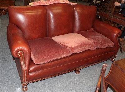 Lot 1422 - A modern red faux leather three-seater sofa