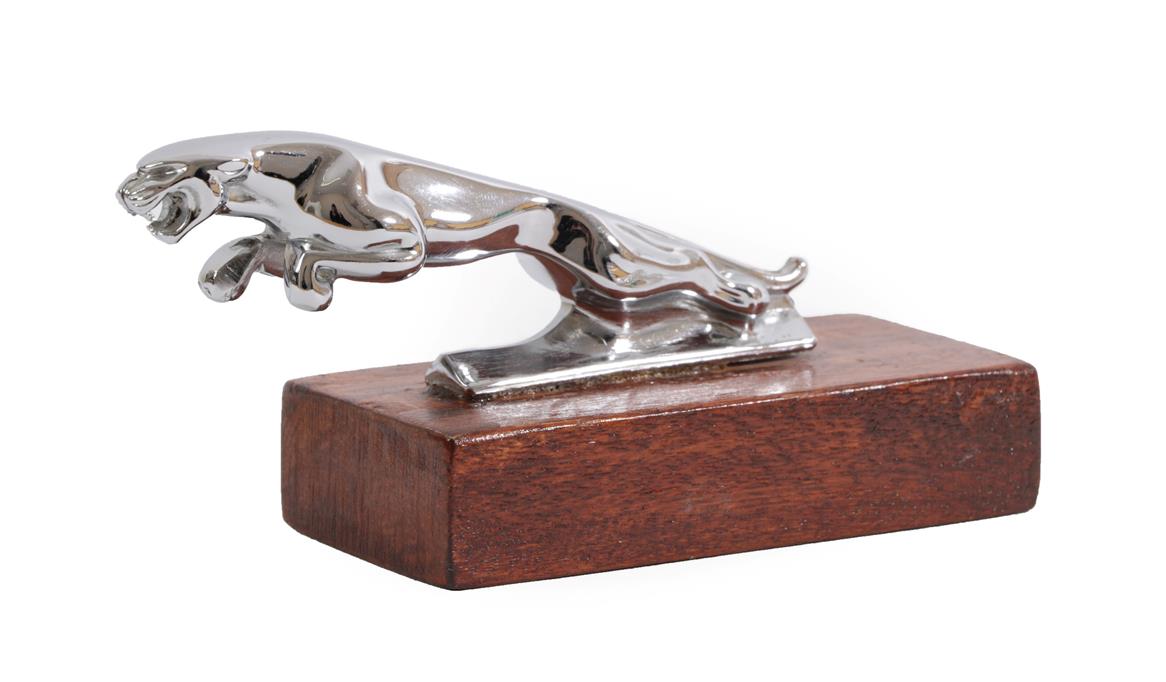 Lot 2036 - A Chrome Car Mascot as a Leaping Jaguar, mounted on a stained wood rectangular base, 13cm long
