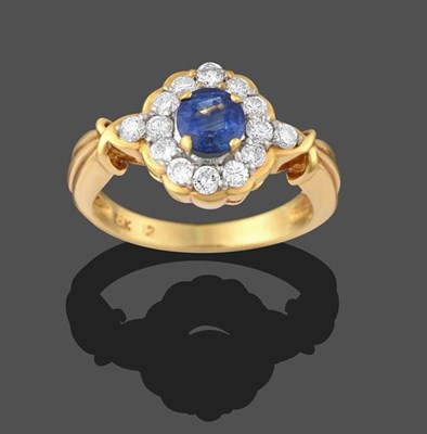 Lot 2152 - A Sapphire and Diamond Cluster Ring, the round cut sapphire in a yellow claw setting, within a...