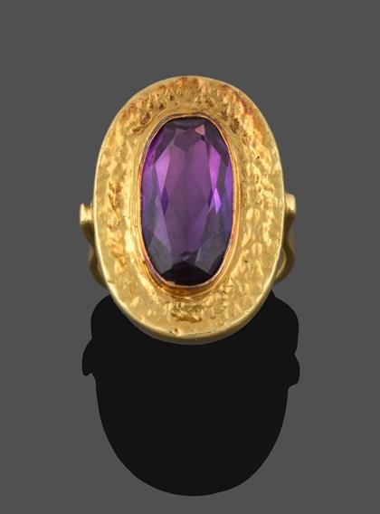 Lot 2188 - An Amethyst Ring, the oval cut amethyst in a yellow rubbed over setting extending to a textured...