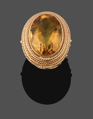 Lot 2192 - A Citrine Ring, the oval cut citrine in a yellow rubbed over setting, within a ropetwist border, to