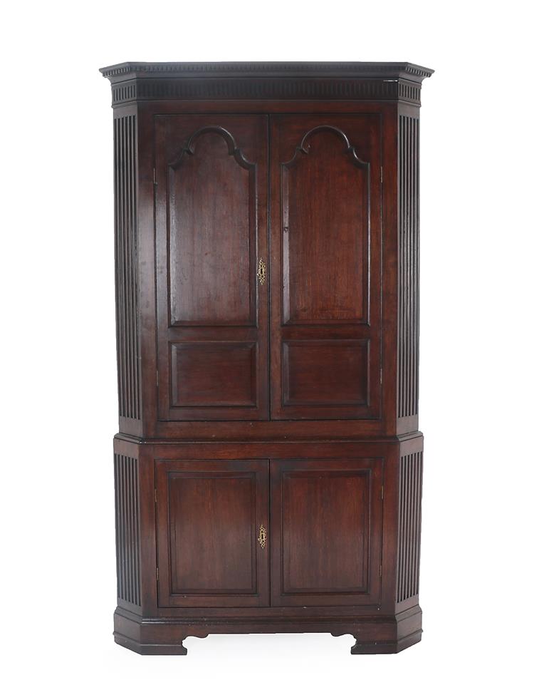 Lot 465 - A George III Oak Free-Standing Corner Cupboard, late 18th century, the dentil and fluted...