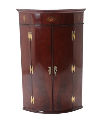 Lot 479 - A George III Mahogany Bowfront Hanging Corner Cupboard, late 18th century, with oval patera...