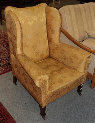 Lot 1203 - A late 19th century wing back chair upholstered in yellow fabric