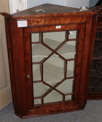 Lot 1254 - A George III elm hanging corner cupboard with glazed door