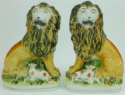 Lot 78 - A Pair of Staffordshire Pottery Figures of Lions, 19th century, each seated, a lamb at its feet, on