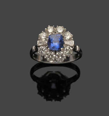 Lot 488 - An 18 Carat White Gold Sapphire and Diamond Cluster Ring, a cushion cut sapphire within a border of