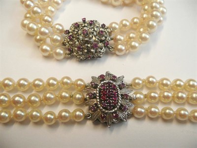 Lot 491 - A Three Row Cultured Pearl Bracelet, knotted to a ruby set floral design clasp, length 18.5cm and A