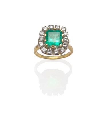 Lot 529 - An Emerald and Diamond Cluster Ring, a step cut emerald in broad yellow claw settings, within a...