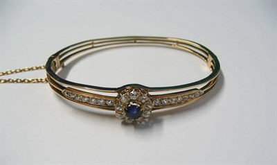 Lot 542 - A Sapphire and Diamond Bangle, a sapphire and old cut diamond cluster centres two lines of old...