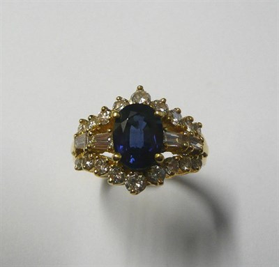 Lot 556 - A Sapphire and Diamond Cluster Ring, an oval mixed cut sapphire within a border of round...