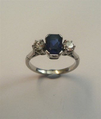 Lot 558 - A Sapphire and Diamond Three Stone Ring, a step cut sapphire flanked by a round brilliant cut...