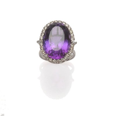 Lot 563 - An 18 Carat White Gold Amethyst and Diamond Cluster Ring, an oval cut amethyst within a border...