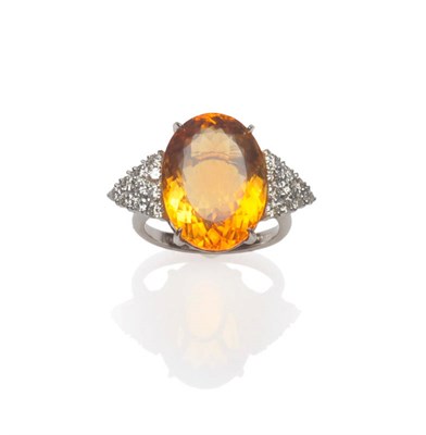 Lot 623 - An 18 Carat White Gold Citrine and Diamond Ring, the oval cut citrine flanked by a cluster of round