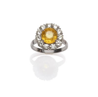 Lot 624 - An 18 Carat White Gold Yellow Sapphire and Diamond Cluster Ring, a round mixed cut yellow...