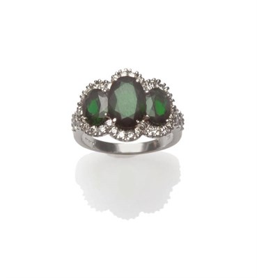 Lot 628 - An 14 Carat White Gold Green Tourmaline and Diamond Ring, three graduated oval cut green...