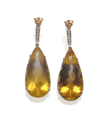 Lot 631 - A Pair of Drop Earrings, a trio of yellow sapphires surmounts a diamond set bar, which suspends...