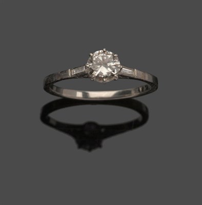 Lot 647 - An Art Deco Diamond Solitaire Ring, the round brilliant cut diamond between a baguette cut...