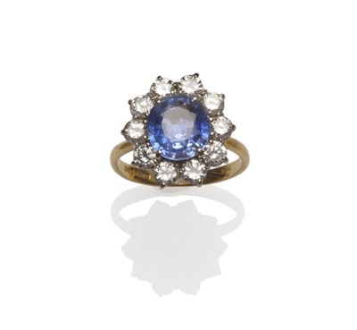 Lot 655 - An 18 Carat Gold Sapphire and Diamond Cluster Ring, the oval mixed cut sapphire within a border...