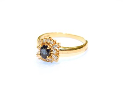 Lot 63 - An 18 carat gold sapphire and diamond cluster ring, the oval cut sapphire within a border of...