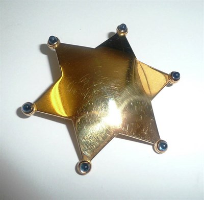 Lot 702 - A Star Brooch, the solid yellow six pointed star with a cabochon sapphire to each point,...