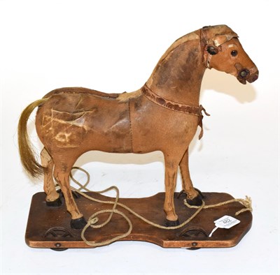 Lot 482 - A late Victorian leather toy pull along horse, raised upon a wooden base with wheels, 32.5cm 33cm