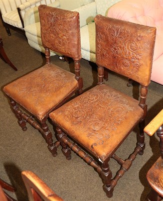 Lot 1344 - A pair of oak chairs with studded and embossed leather work decorated with leaves and scrolls