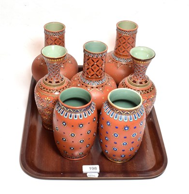 Lot 198 - Mettlach comprising two pairs of vases and three other vases, all with iron red ground and...