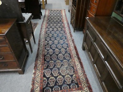 Lot 1131 - A North West Persian runner, the indigo field of Boteh enclosed by narrow ivory borders, 437cm...