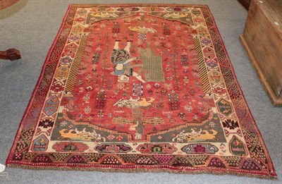 Lot 1146 - A Kashgai rug, the raspberry field depicting a scene from Persepolis enclosed by spandrels and...