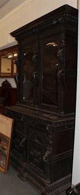 Lot 1230 - A Victorian ornately carved oak bookcase cabinet, the upper section with two glazed doors,...
