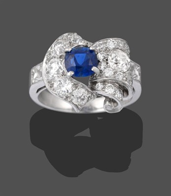 Lot 2210 - A Sapphire and Diamond Cluster Ring, the central round cut sapphire in a white claw setting, within