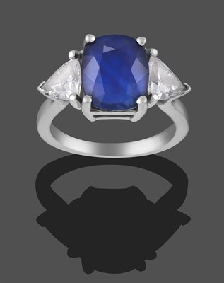 Lot 2300 - A Sapphire and Diamond Three Stone Ring, the cushion cut sapphire flanked by two trilliant cut...