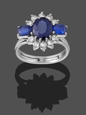 Lot 2303 - A Sapphire and Diamond Cluster Ring, by Graff, circa 1960, the oval cut sapphire flanked by two...