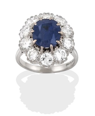 Lot 2320 - An 18 Carat White Gold Sapphire and Diamond Cluster Ring, the oval cut sapphire within a border...