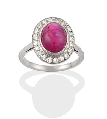 Lot 2330 - A Ruby and Diamond Cluster Ring, the cabochon ruby in a white rubbed over setting, within a...