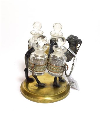 Lot 190 - A set of four cut-glass scent bottles on a metal stand cast as a camel and with a round brass base