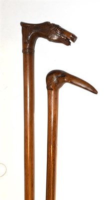 Lot 356 - Two carved walking sticks, one in the form of a horses head with saddle, the other as a bird