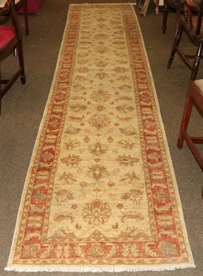 Lot 1002 - Narrow Afghan runner, the cream field of palmettes and flowering vines enclosed by terracotta...
