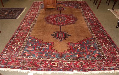 Lot 1003 - Heriz Carpet, the camel ground centred by a medallion framed by spandrels and scarlet borders,...