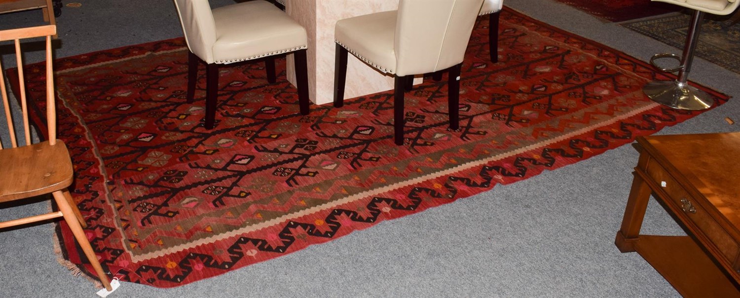 Lot 1005 - Large Anatloian Kilim, the tomato red field with a one way design of angular trees enclosed by...