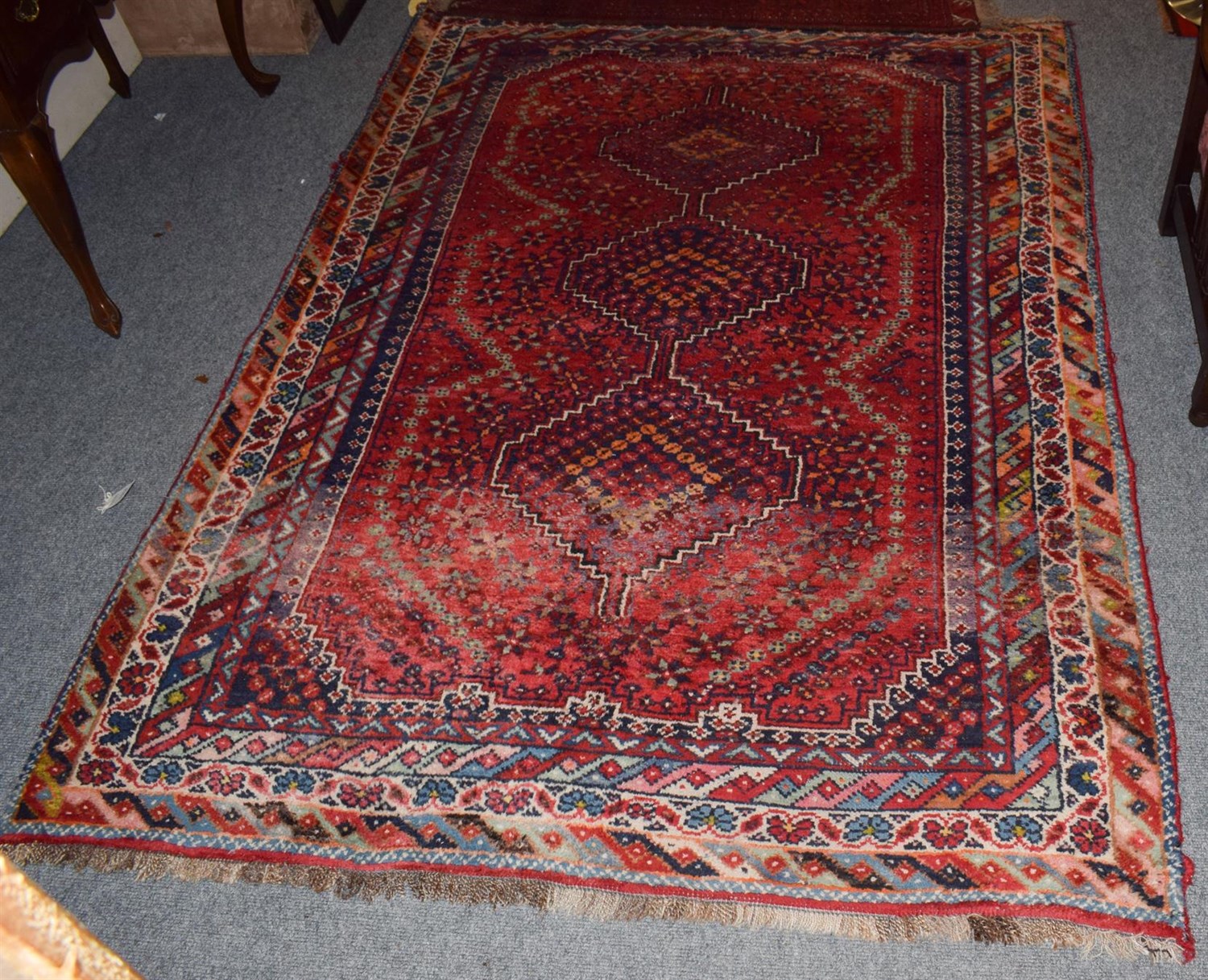 Lot 1014 - A Kashgai rug, the scarlet field with three stepped medallions enclosed by multiple borders,...
