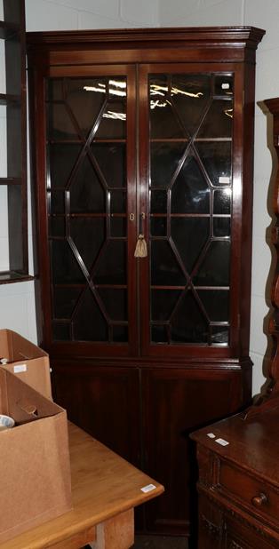 Lot 1157 - A late George III mahogany floor standing corner cupboard, with a moulded cornice over an...
